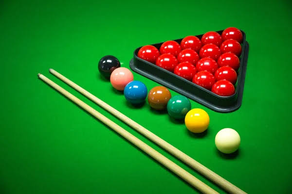 Snooker balls, triangle and cues laid out on green cloth